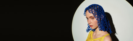 A stunning young woman showcases unique fashion and striking hair against a contrasting background.の写真素材