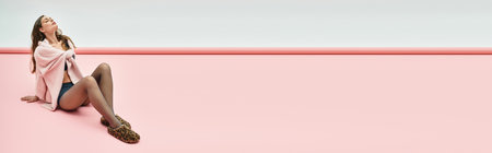 Graceful young woman savors a calm moment on a vibrant pink floor, wrapped in soft fabric.の写真素材