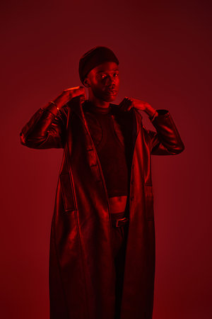 A young African American man poses stylishly in stunning red light.の写真素材