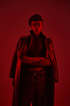 A young african american man shows off his vibrant style and confidence in a bold red setting.の写真素材