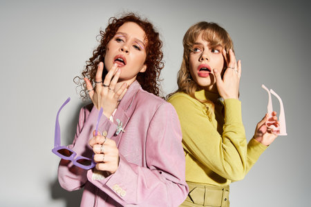 Two young women share love and joy through playful poses and vibrant fashion styles.の写真素材