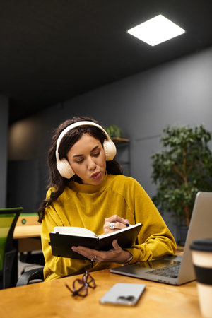 Beautiful and elegant young woman focuses on her notebook in a stylish office setting.