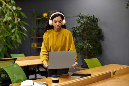 Young woman focuses on her laptop while enjoying a peaceful moment in an elegant office space.