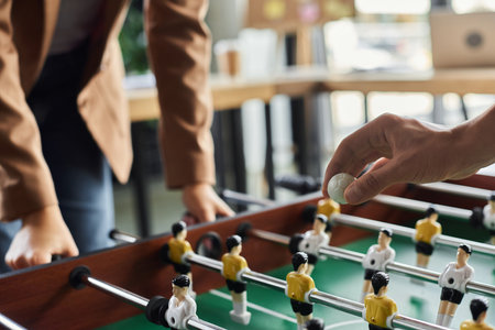 Two colleagues focus intently on a foosball game, showcasing teamwork and lighthearted competition.