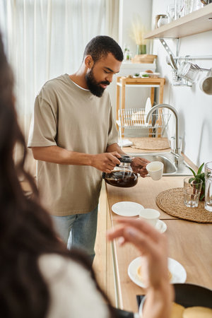 A couple enjoys their morning routine, brewing coffee and preparing breakfast in a cozy kitchen.の写真素材