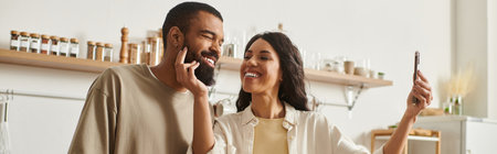 A couple shares a joyful moment together in their cozy home while taking a playful selfie.のeditorial素材