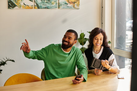 An African American couple shares laughs and drinks at a sunny cafe while reading the menu.の写真素材