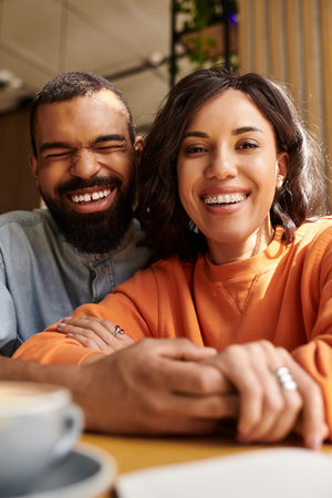An African American couple enjoys their time together, exchanging smiles and laughter in a cafe.の写真素材