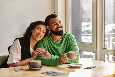 An African American couple enjoys each other's company over coffee in a cozy cafe.