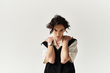 A handsome young man showcases a trendy outfit while striking a contemplative pose in the studio.のeditorial素材