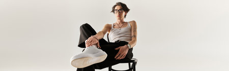 Stylish young man sits confidently in a studio, displaying casual fashion in a sleek outfit, banner