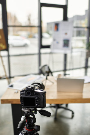 A well organized workspace displays a camera on a tripod next to a laptop and project materials.の写真素材