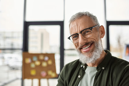 A cheerful man engages with coworkers in a bright office environment filled with creativity.のeditorial素材