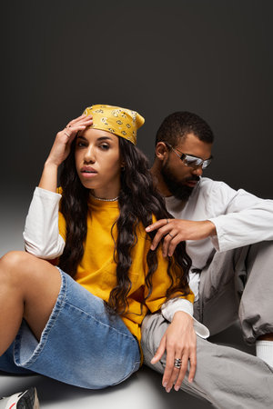 A fashionable pair sitting closely, showcasing their bond and unique sense of style.