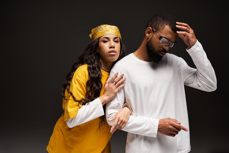 A fashionable couple expresses love and connection against a dark, moody backdrop.の写真素材