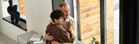 A middle-aged couple shares joy as they embrace in their warm, inviting living space, banner