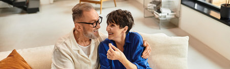 A husband and wife exchange smiles and laughter while enjoying their cozy living space, banner