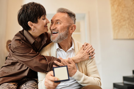 A happy couple embraces each other warmly while celebrating together in their cozy home.の写真素材