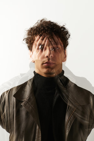 A young, handsome man stands confidently against a plain backdrop, showcasing his unique style.