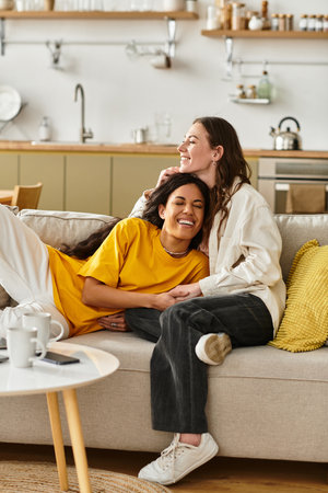 Two women smile and embrace while enjoying each others company in their inviting living room.の写真素材