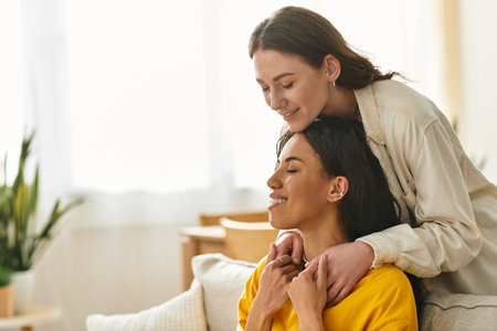 Two women share a loving moment at home, enjoying each others company in a cozy atmosphere.の写真素材
