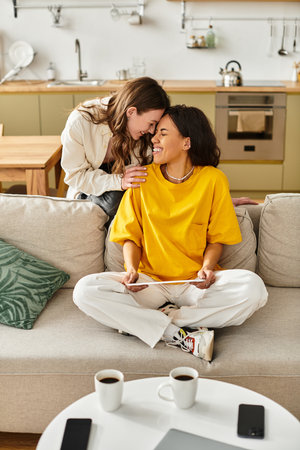 Two women share a joyful moment, creating a warm atmosphere at home filled with love.の写真素材