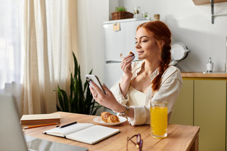 A red haired woman smiles while enjoying breakfast in a cozy kitchen filled with morning light.のeditorial素材