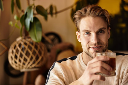 A charming man relaxes with a drink in hand, enjoying the warm ambiance and decor.