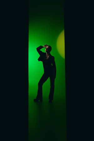 A young woman showcases her fashion sense in a chic black outfit against lush green hues.
