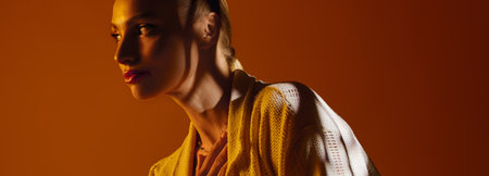 Radiant young woman highlights modern fashion in warm, vivid lighting for a stunning look.のeditorial素材
