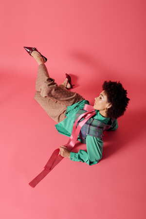 A young woman displays her unique style in a trendy pose against a pink backdrop.のeditorial素材