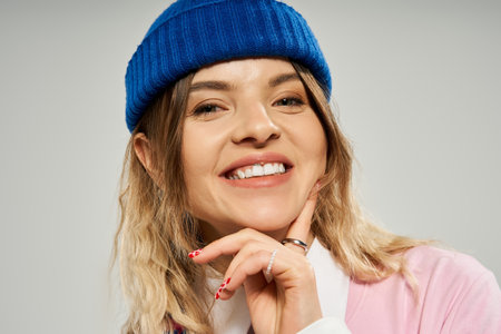A young woman shines with joy in a vibrant stylish ensemble while wearing a beanie.