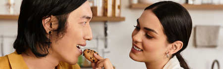 A couple smiles as they feed each other cookies in their cozy kitchen.