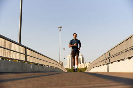 With a determined expression, a young man jogs confidently on an empty street, showcasing vitality.の写真素材