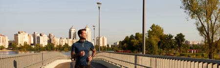 A handsome young man strolls leisurely on a vibrant walkway, feeling the warmth of the sun.