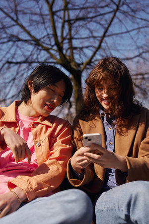 Two young friends share a joyful moment in the park, soaking up the sun and laughter.