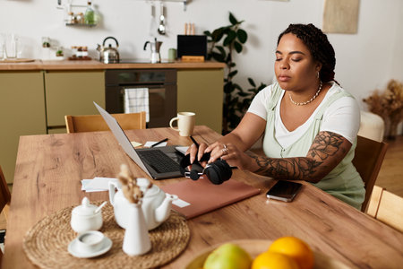 Focused young woman works on her laptop at home, creating a cozy freelance environment.の写真素材