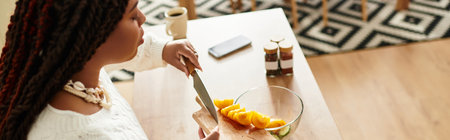 A young African American woman skilfully prepares a fresh salad in her cozy kitchen, banner