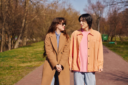 Two young friends reflect happiness while walking in a park during a sunny day.