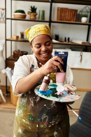 A beautiful woman joyfully mixes paint on a palette while surrounded by crafting supplies.の写真素材