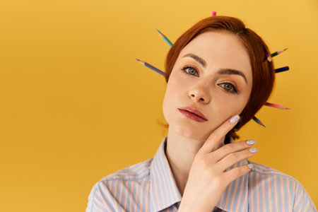 A beautiful young woman showcases creativity with vibrant pencils in her hair against a yellow wall.