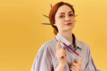 A young woman playfully showcases colorful pencils in her hair, radiating creativity.の写真素材