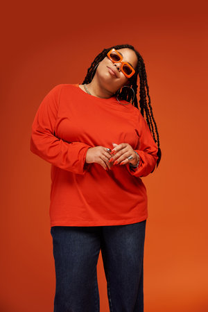 A serene moment captures a trendy woman in a bold outfit, exuding carefree bliss in her pose.