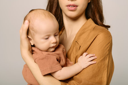 A young mother cradles her baby tenderly while sharing a moment of love in a cozy environment.の写真素材