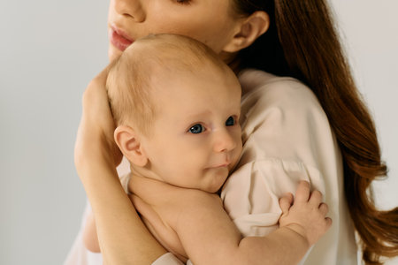 A young mother holds her child close, exuding warmth in a cozy atmosphere.