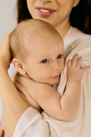 A young mother lovingly holds her child, exuding warmth in a cozy setting.