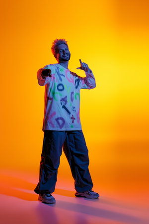 Handsome young man poses playfully against a bright, artistic background.