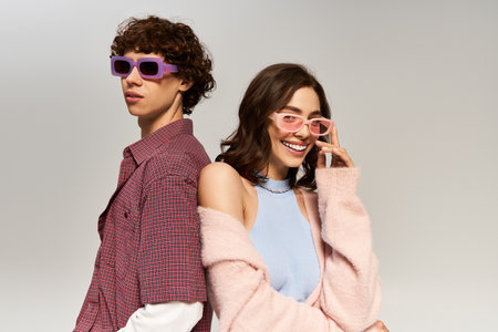A young couple stands together showcasing their fashion sense, exuding joy and love.