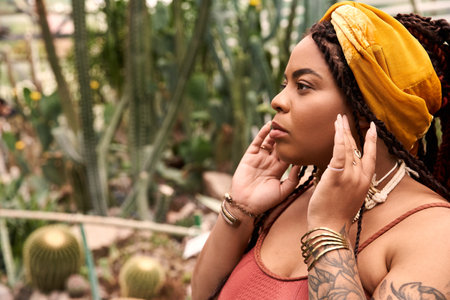 A joyful African American woman with braids enjoys a peaceful moment surrounded by lush plants.
