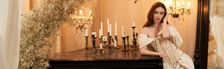 A blissful young woman in an elegant vintage dress poses gracefully amid soft candlelight, bannerの写真素材